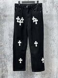 Chrome pants in dark denim with white cross and clover-style patches, front view