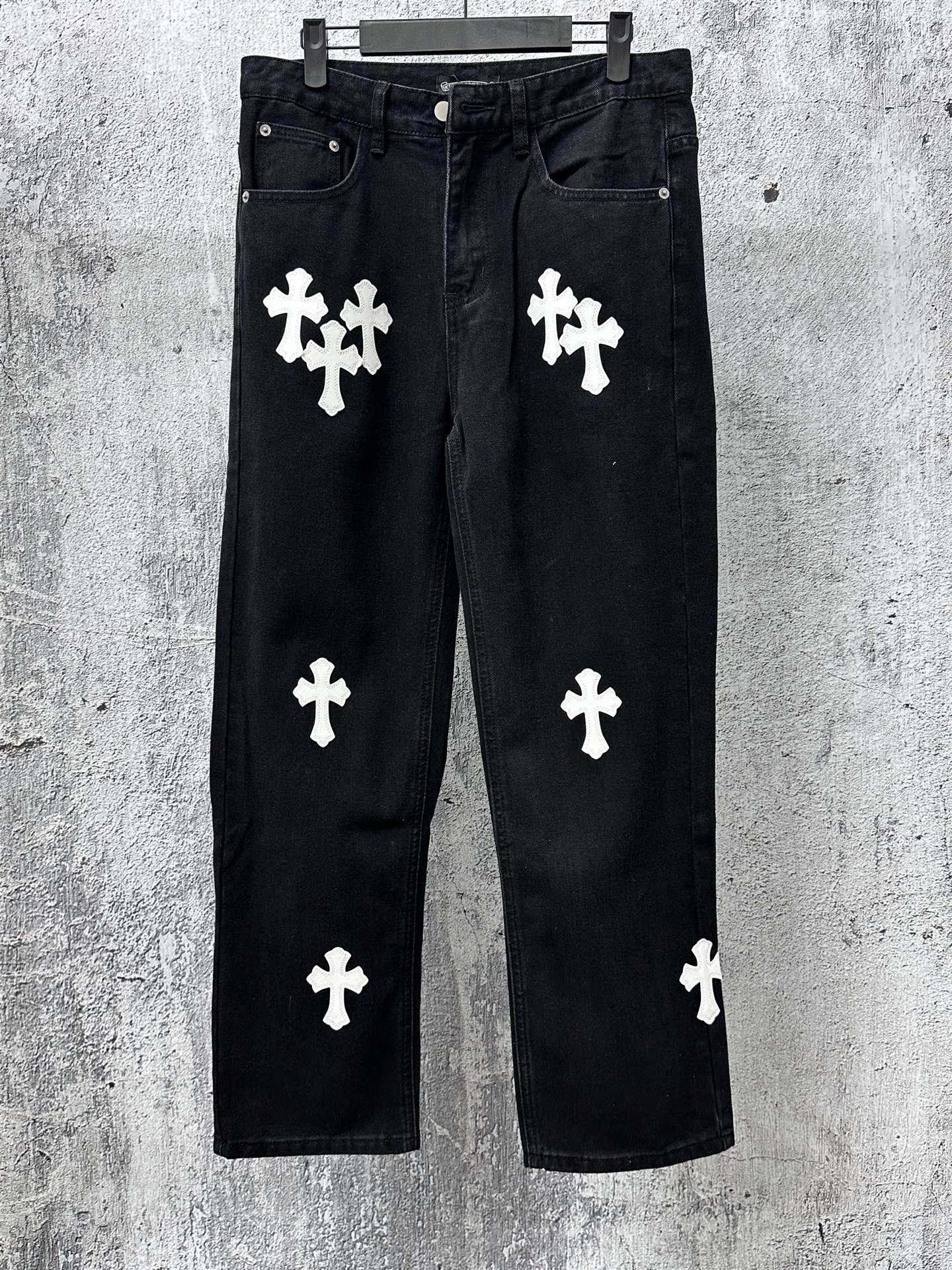 Chrome pants in dark denim with white cross and clover-style patches, front view