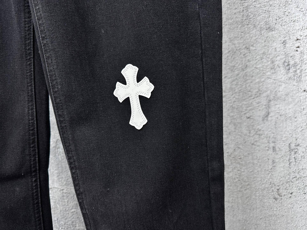 Dark denim pants with small white cross patch on thigh