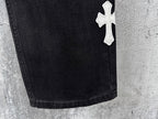 Dark denim pants hem with small white cross patch near lower leg