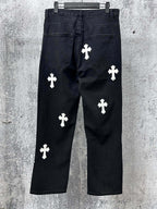 Dark denim pants with white cross applique patterns, side front view