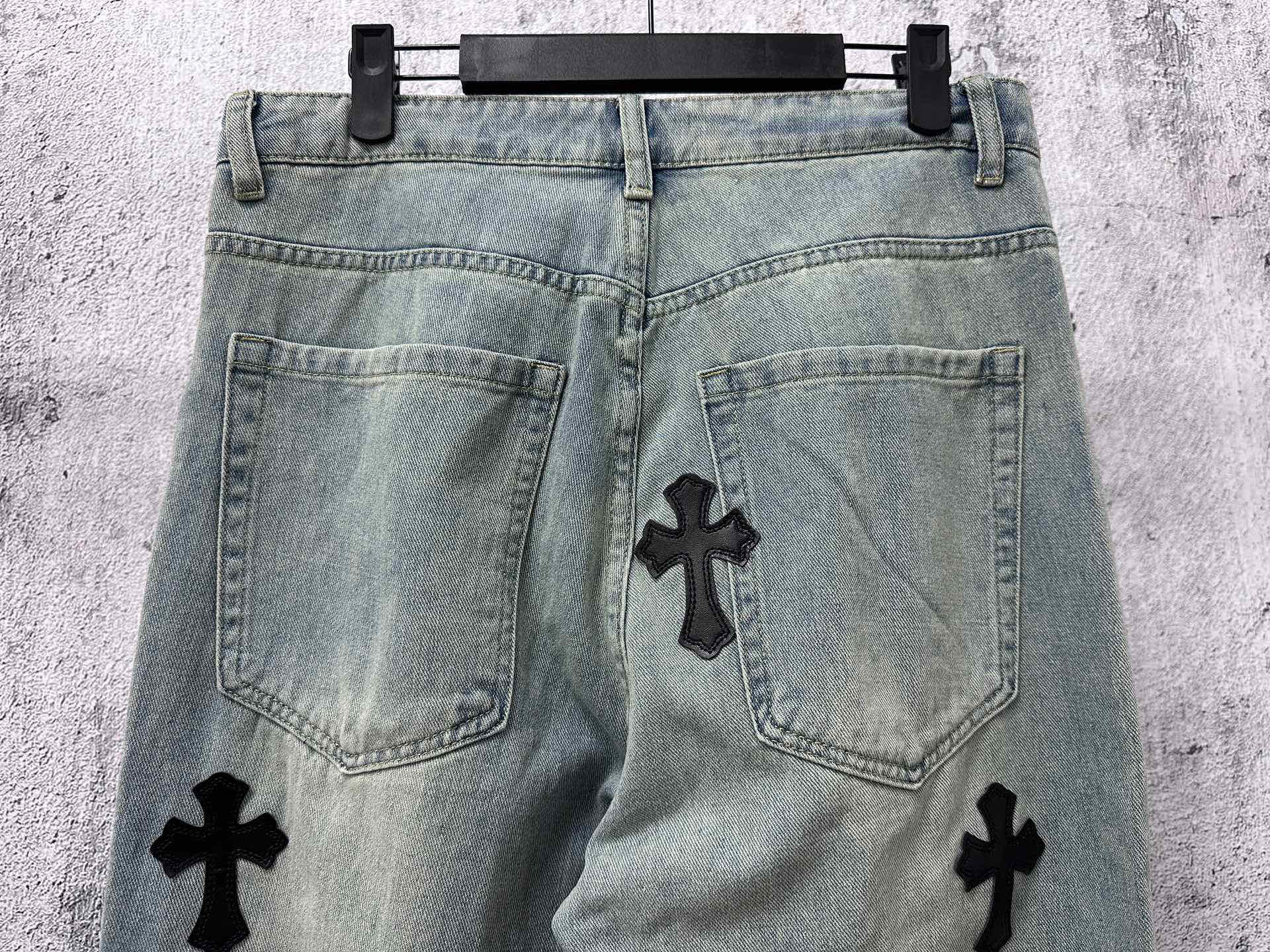 Light blue denim pants back view with pockets and black cross patches