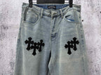 Light blue denim pants with black cross patches on both legs