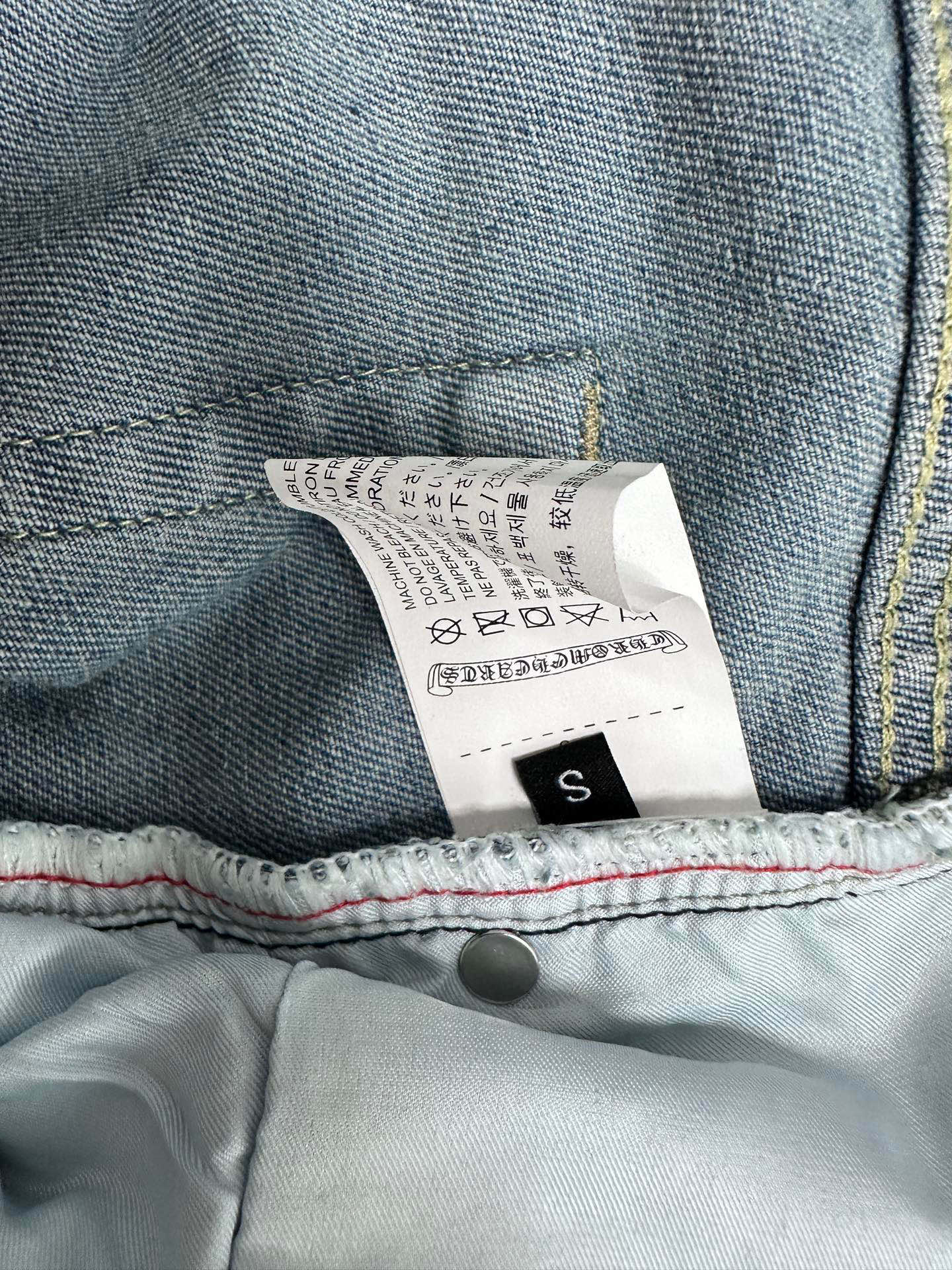 Light blue denim pants with size label and care tag, size S
