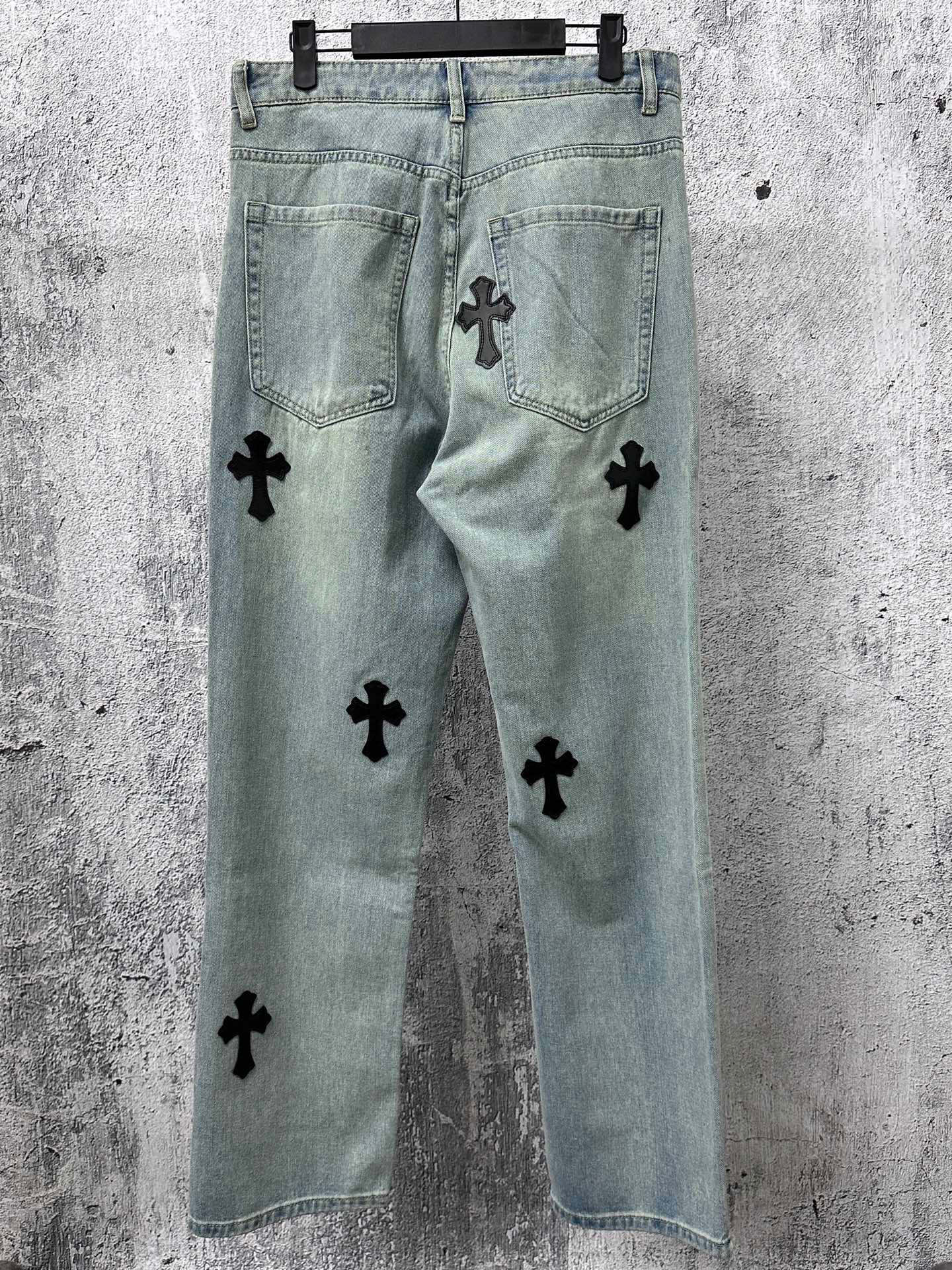 Light blue denim pants with black cross patches on front