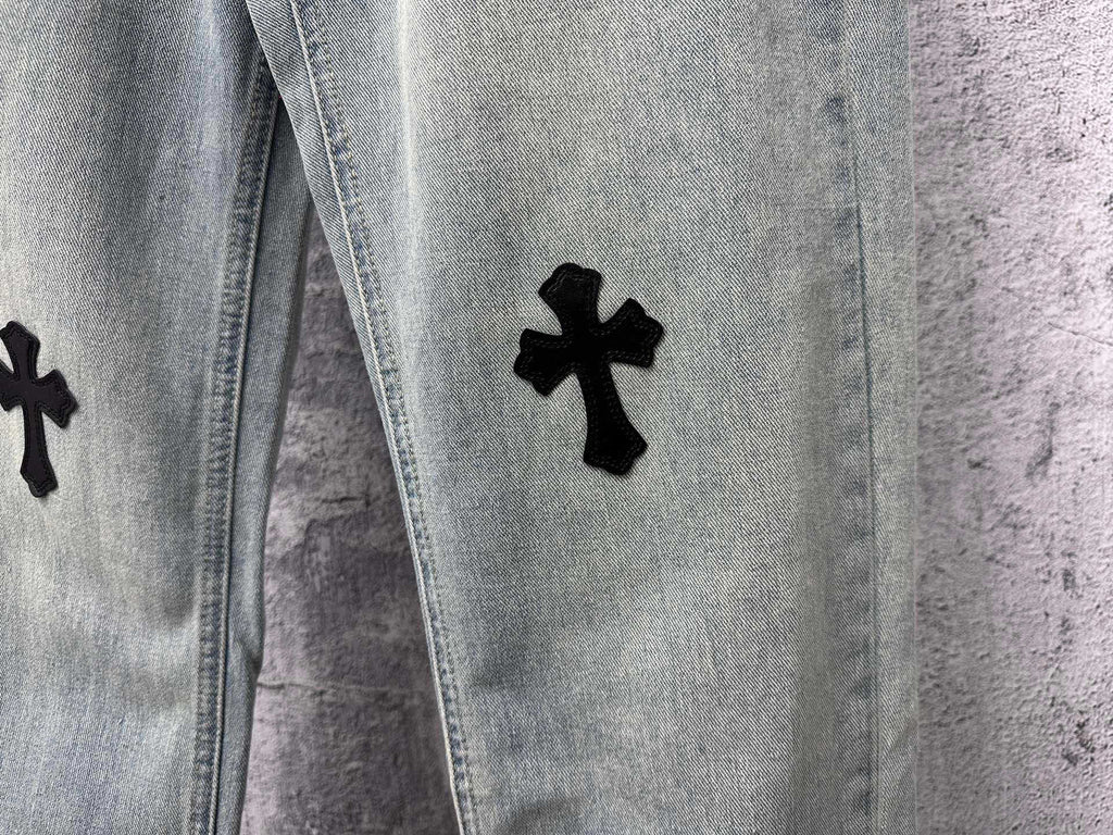 Light blue denim pants with a black cross patch on the leg