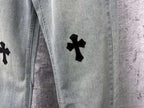 Light blue denim pants with a black cross patch on the leg