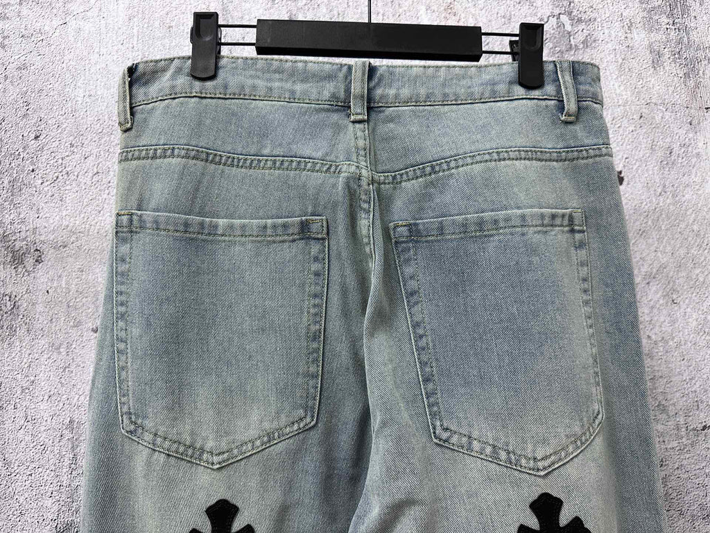 Light-wash denim pants with front pockets and small cross patches on legs