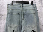 Light-wash denim pants with front pockets and small cross patches on legs