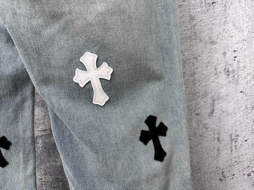 Light-wash denim leg with a white cross patch and a black cross patch