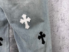Light-wash denim leg with a white cross patch and a black cross patch