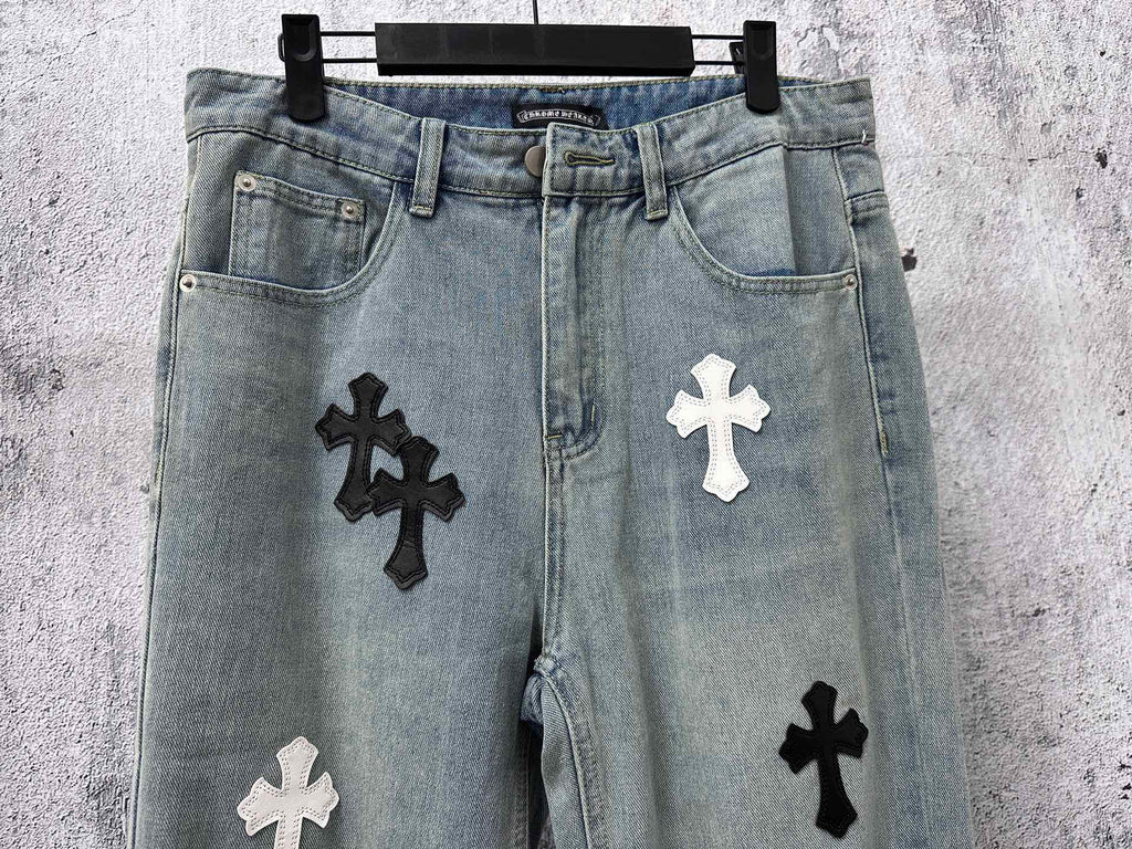 Light-wash denim pants with black and white cross patches near the thighs