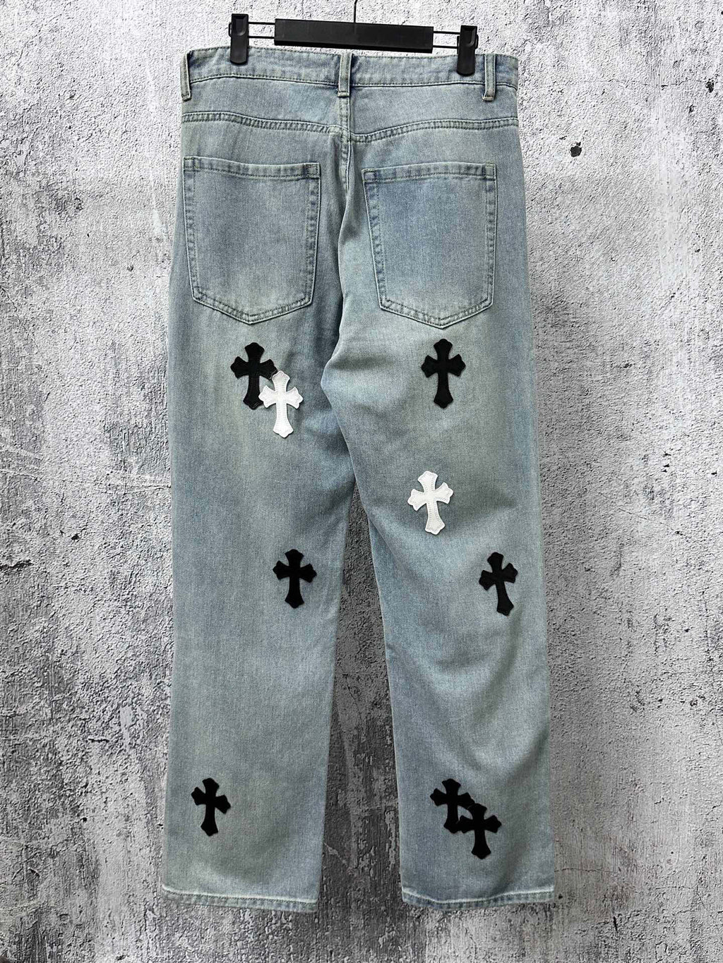Light-wash denim pants with scattered cross patches and back pockets