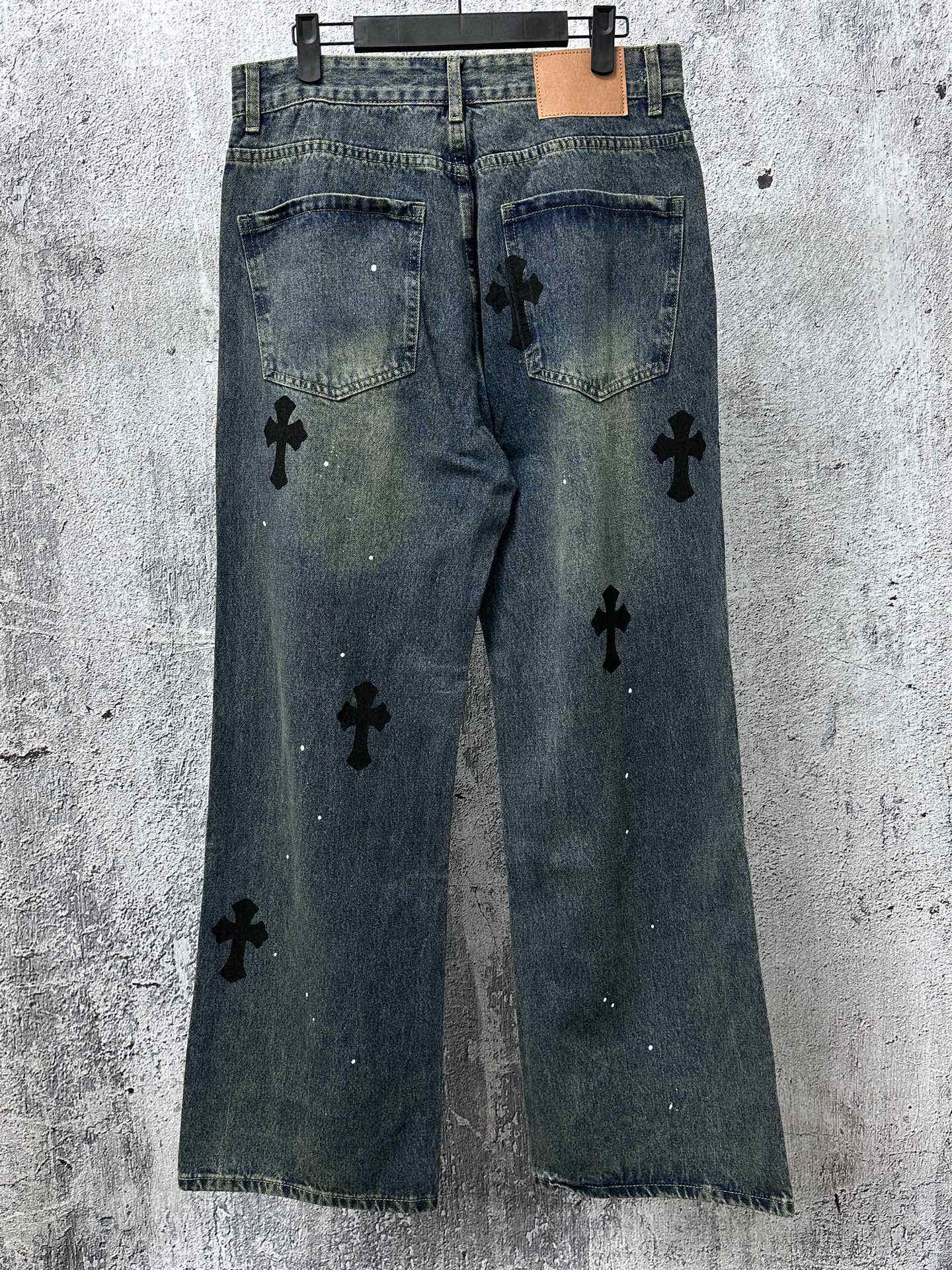 Blue denim jeans pants with black cross-like graphic patches and front pockets