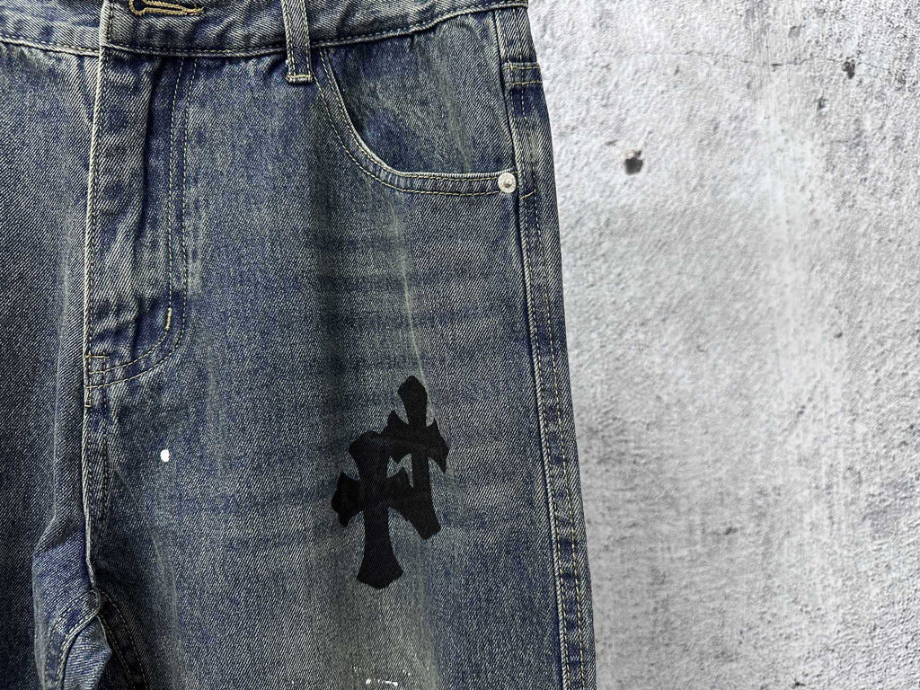 Blue denim jeans with black cross graphic near the front pocket