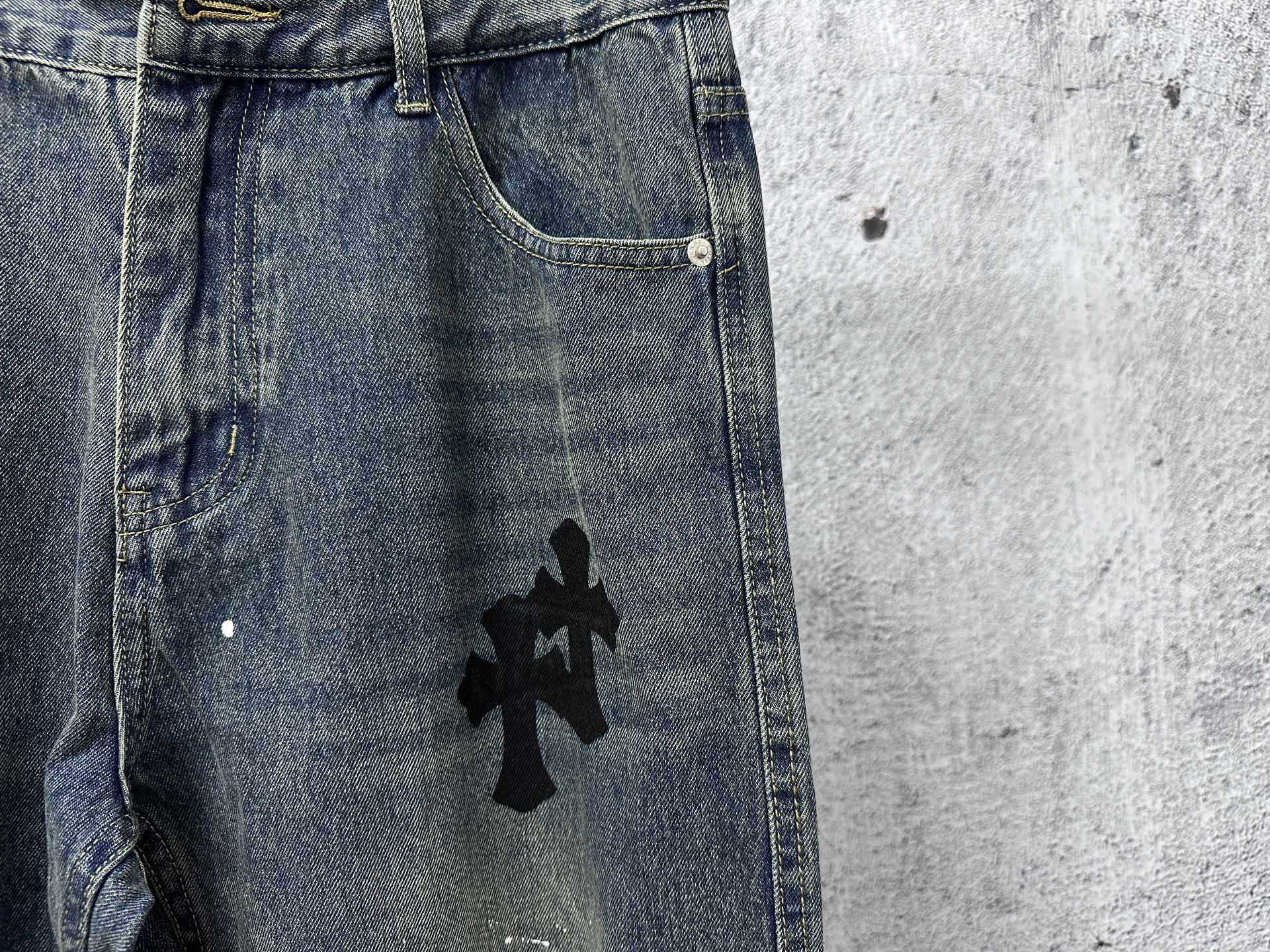 Blue denim jeans with black cross graphic near the front pocket
