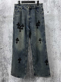 Blue denim jeans pants with black cross-like graphic patches on the legs