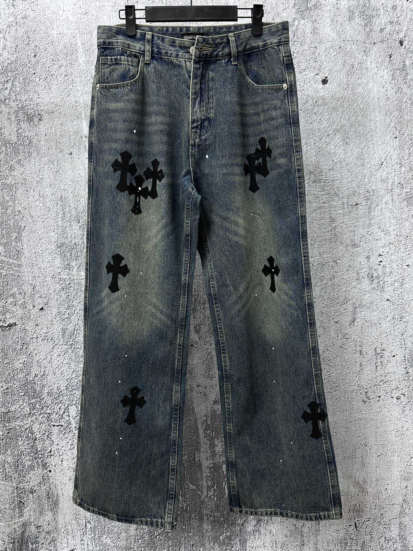 Blue denim jeans pants with black cross-like graphic patches on the legs