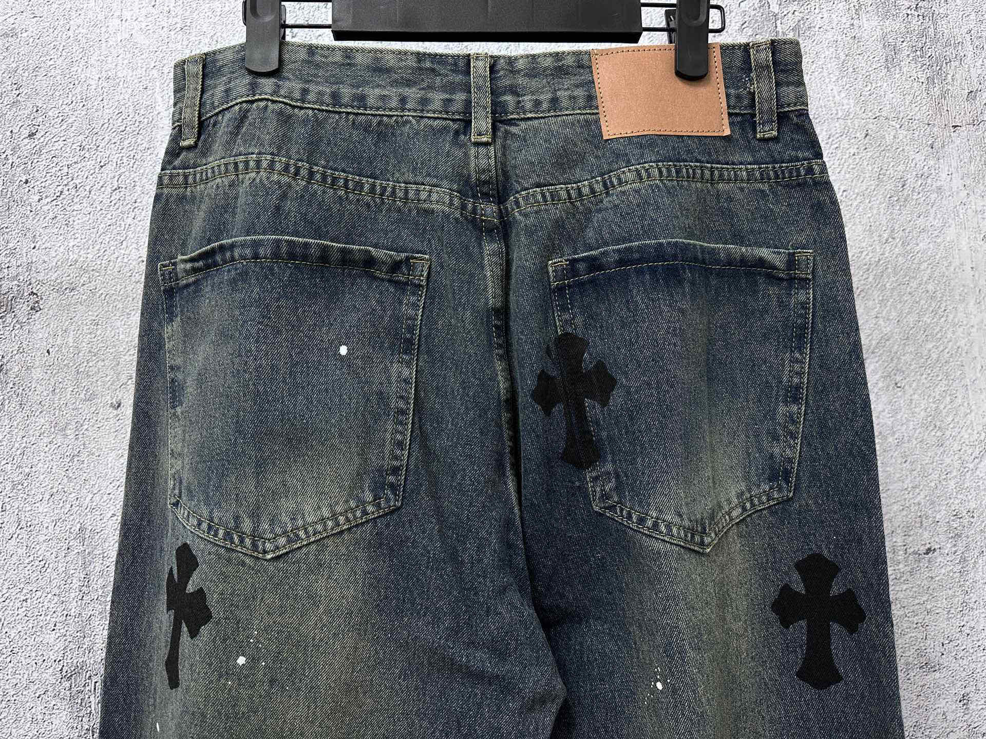 Blue denim jeans pants with two back pockets and black cross graphic patches