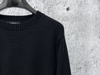 Black knit sweater with ribbed neckline and textured sleeve knit