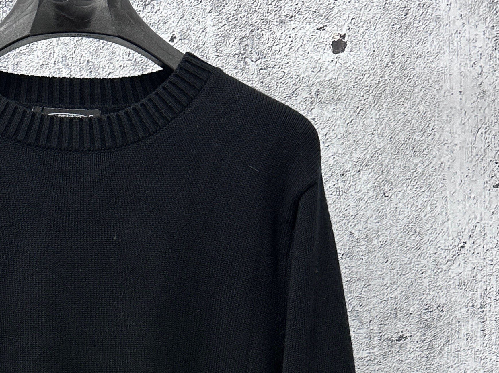 Black knit sweater with ribbed neckline and textured sleeve knit