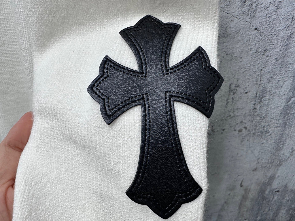 Black cross applique patch on light sweater fabric