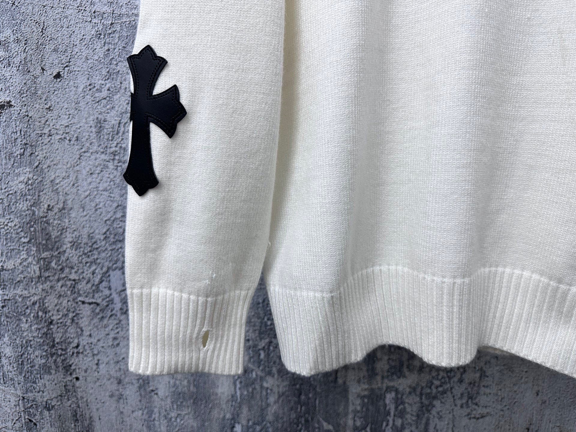 Light long-sleeve sweater with black cross detail on sleeve cuff