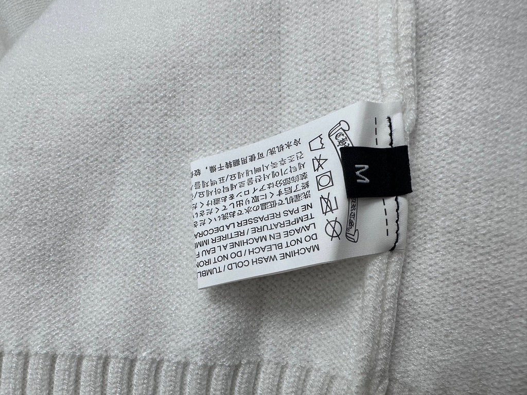 Light sweater fabric care label sewn inside neck