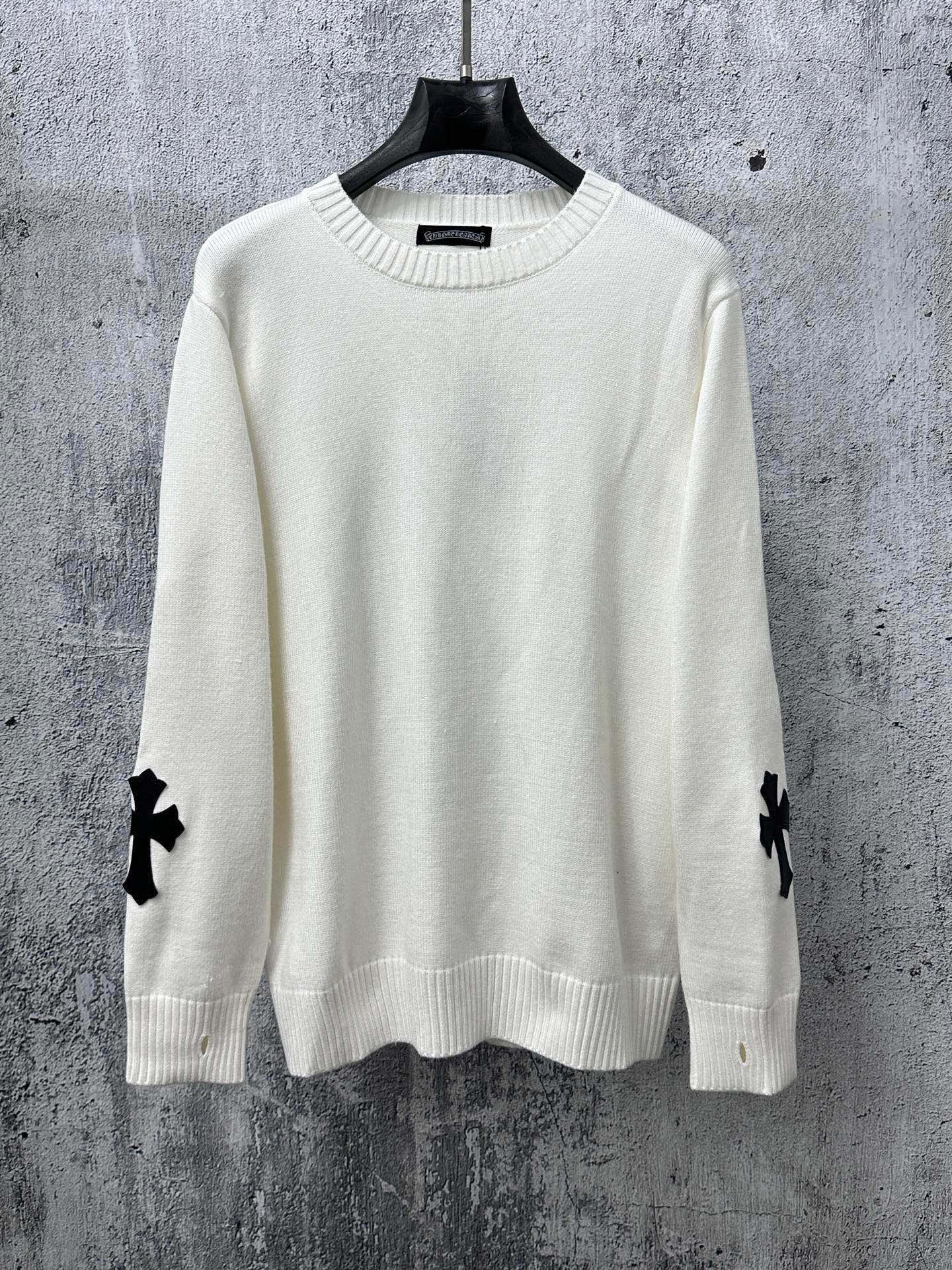 Light long-sleeve sweater with crew neck and black cross patches on sleeves