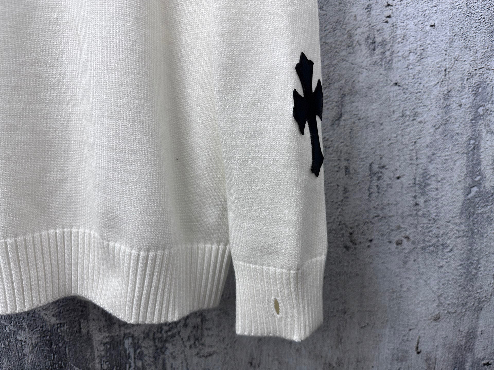 Light long-sleeve sweater with black cross detail and ribbed cuff