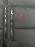 Dark puffer jacket front close-up with visible zip track and small red logo