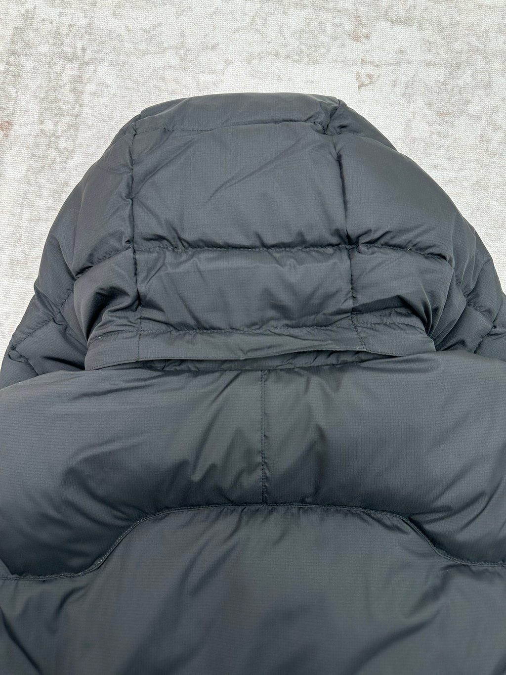 Dark puffer jacket hood and upper back close-up with quilted stitching