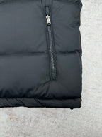 Dark puffer jacket lower side close-up with zipper and button detail