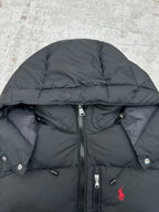 Dark puffer jacket close-up with full-zip and snap buttons, red logo on chest
