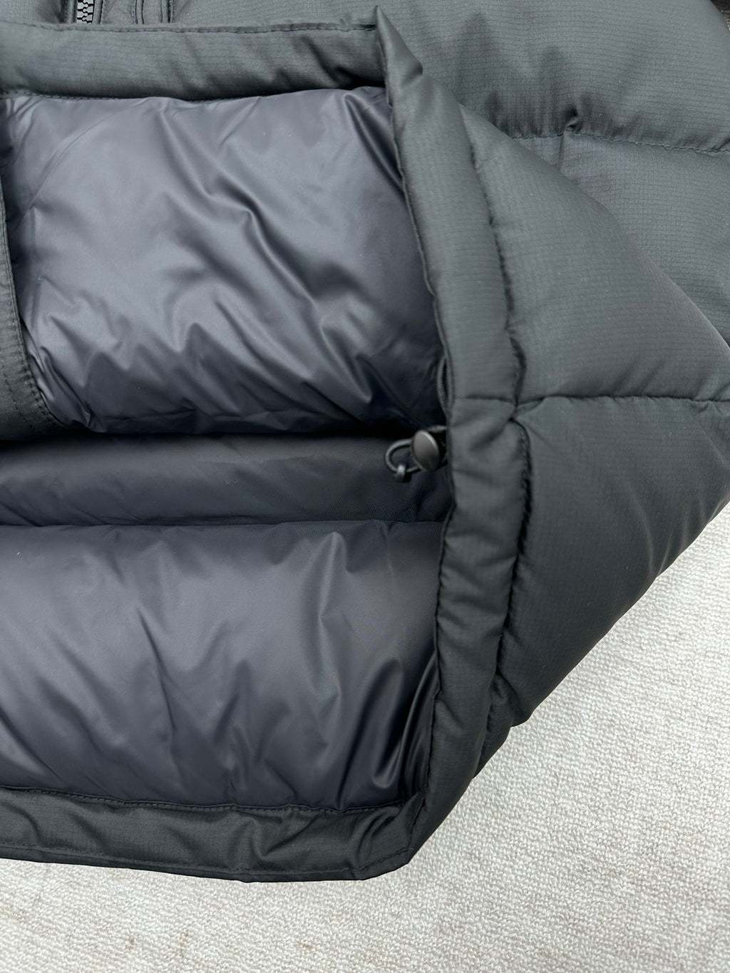 Dark puffer jacket seam and drawcord close-up on quilted panel
