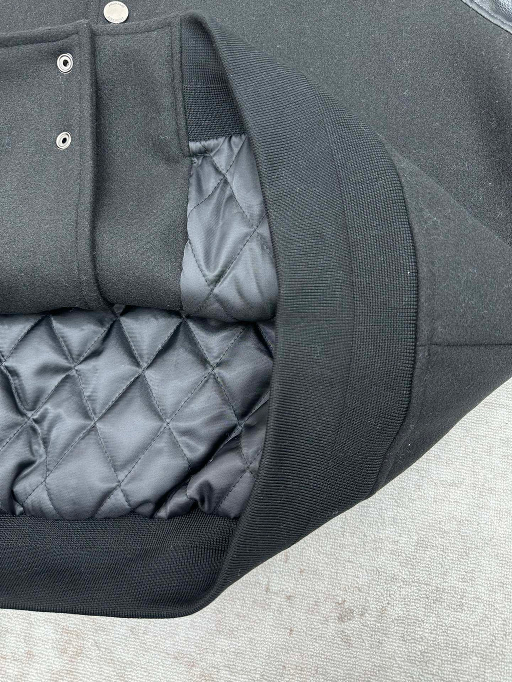 Black bomber jacket showing quilted gray lining and ribbed inner trim