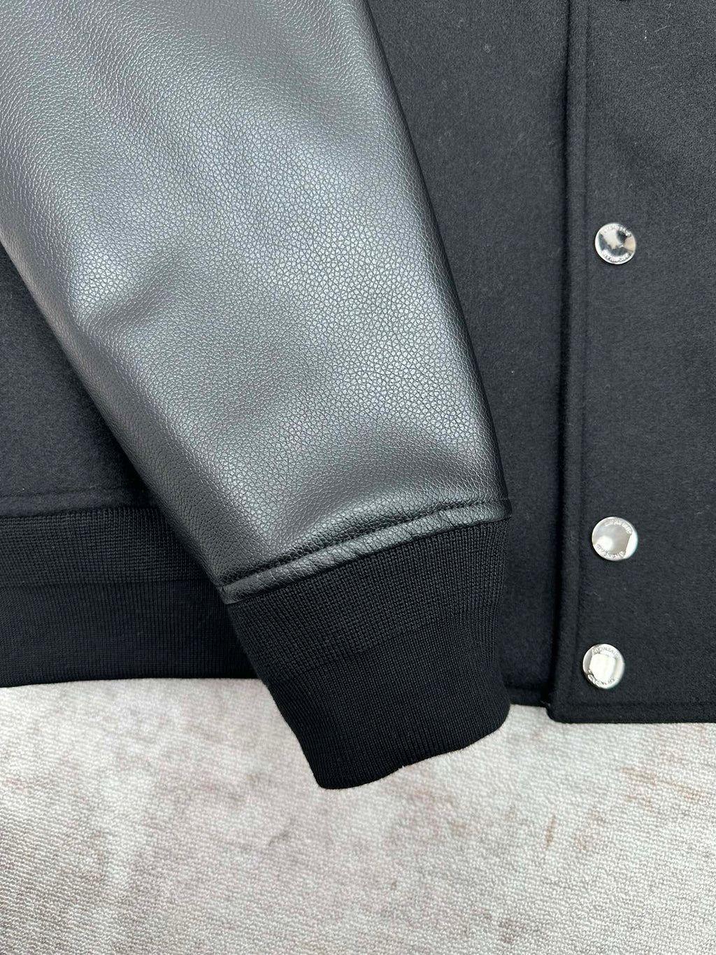Black bomber jacket sleeve with ribbed cuff and silver snap buttons
