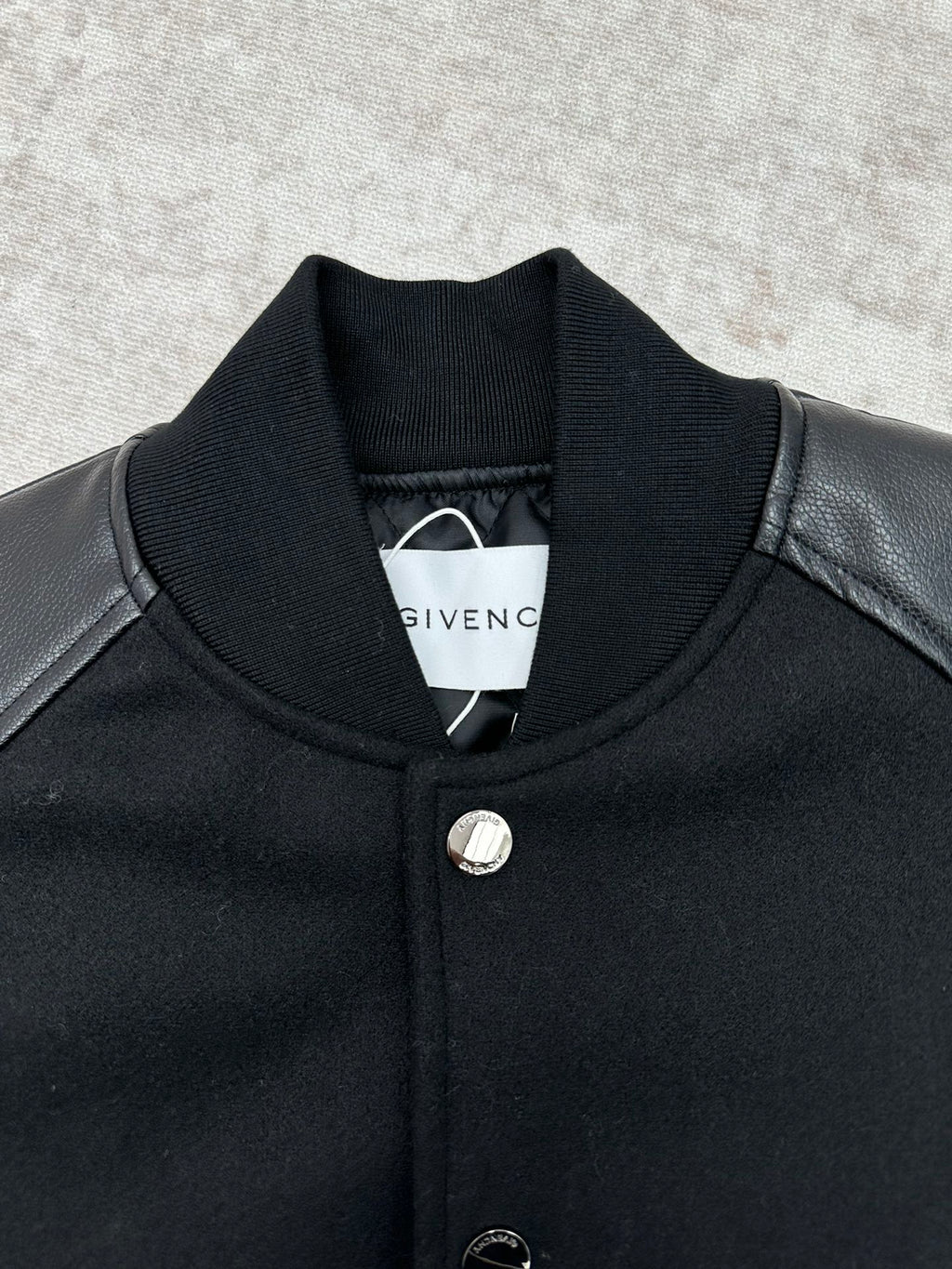 Black bomber jacket with stand collar, snap buttons, and round metal emblem