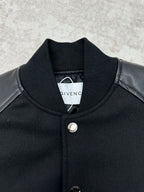 Black bomber jacket with stand collar, snap buttons, and round metal emblem