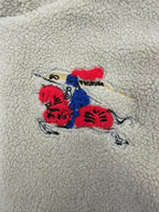 Colorful embroidered graphic on cream sherpa jacket: red, blue and black motif