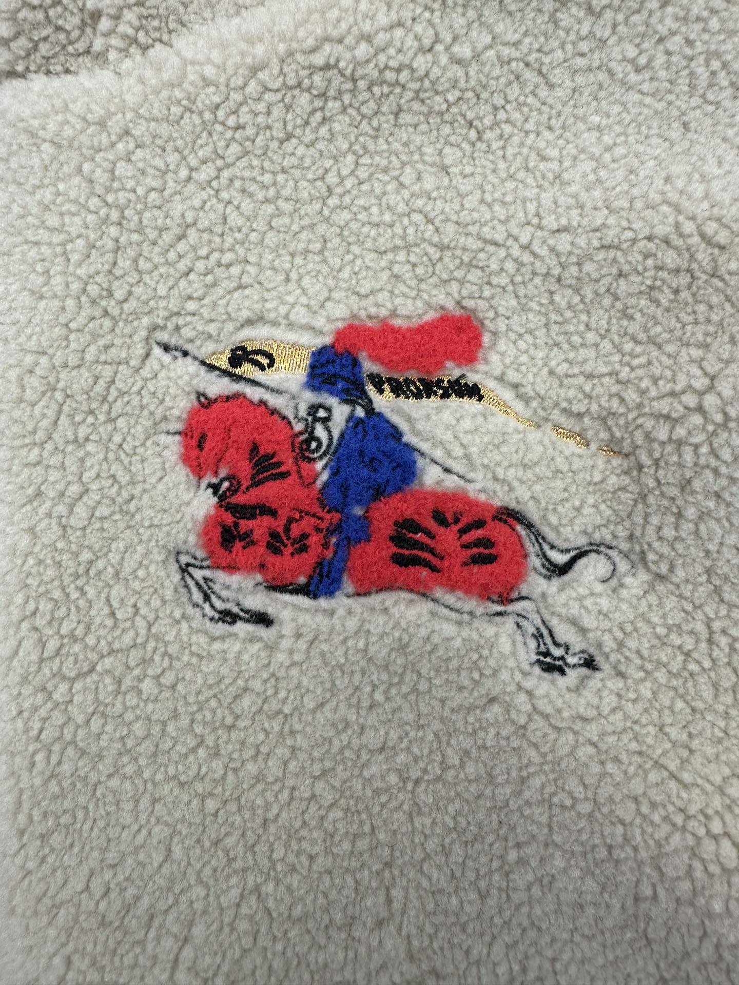 Colorful embroidered graphic on cream sherpa jacket: red, blue and black motif