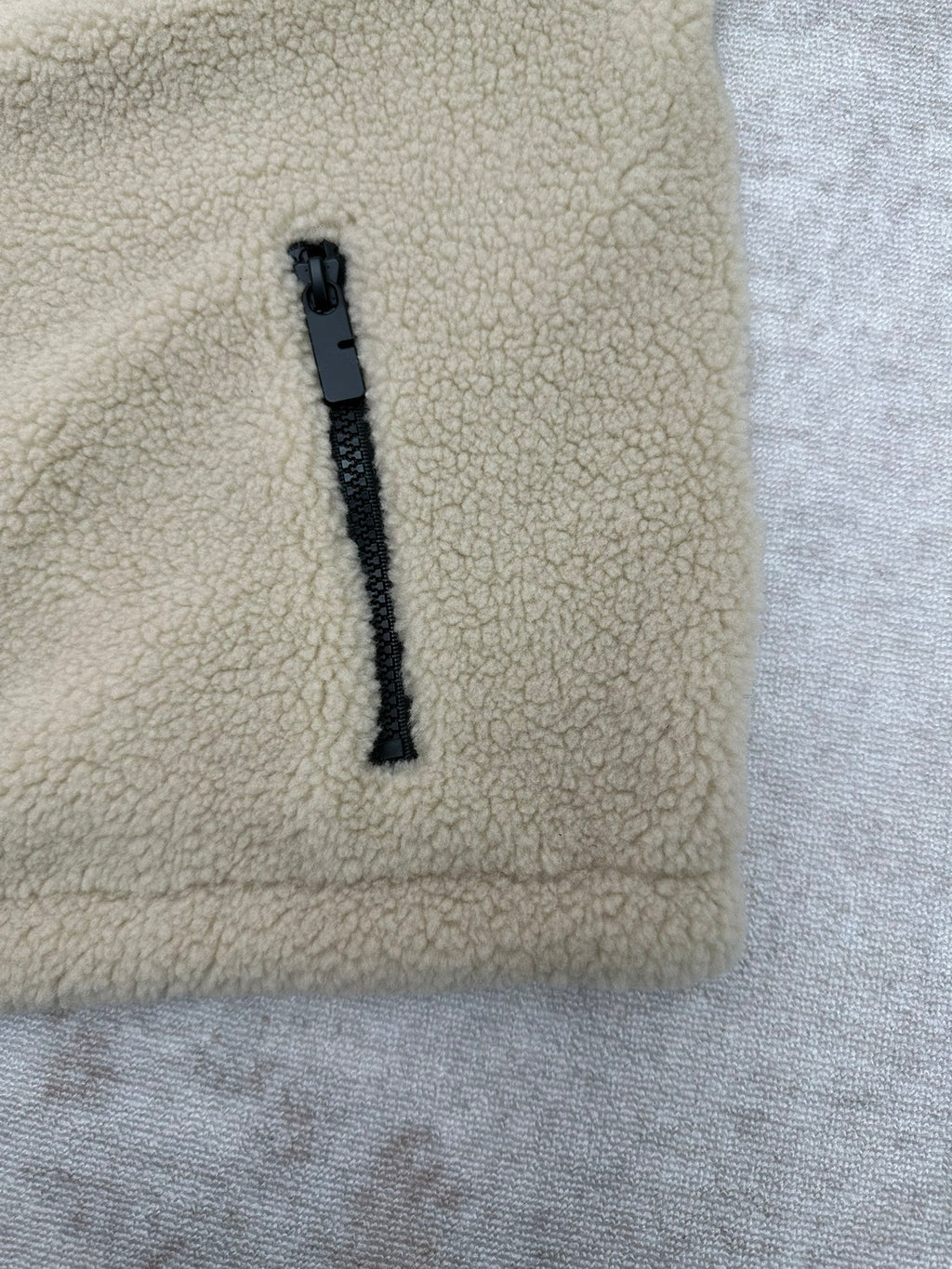 Cream sherpa jacket front with dark zipper trim and pull tab