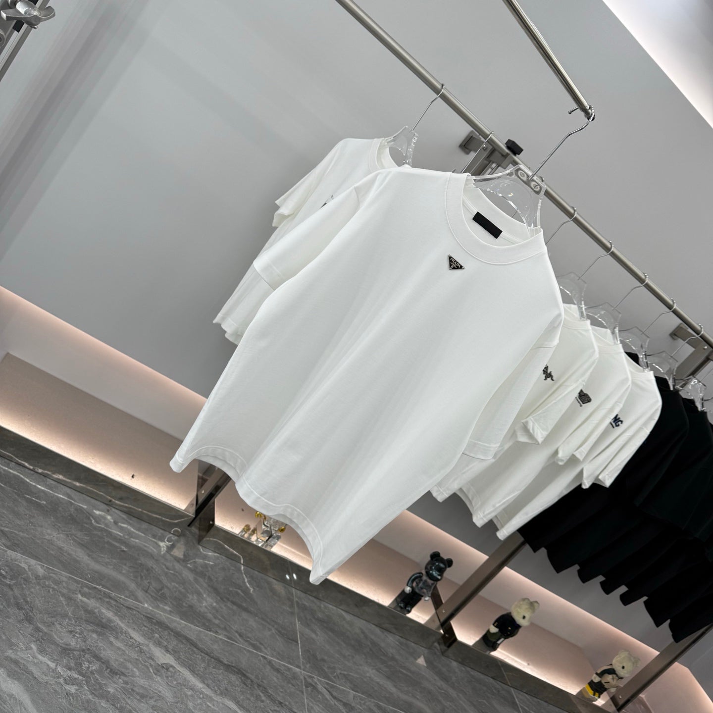 White short-sleeve T-shirt on hanger, triangular Prada badge at chest