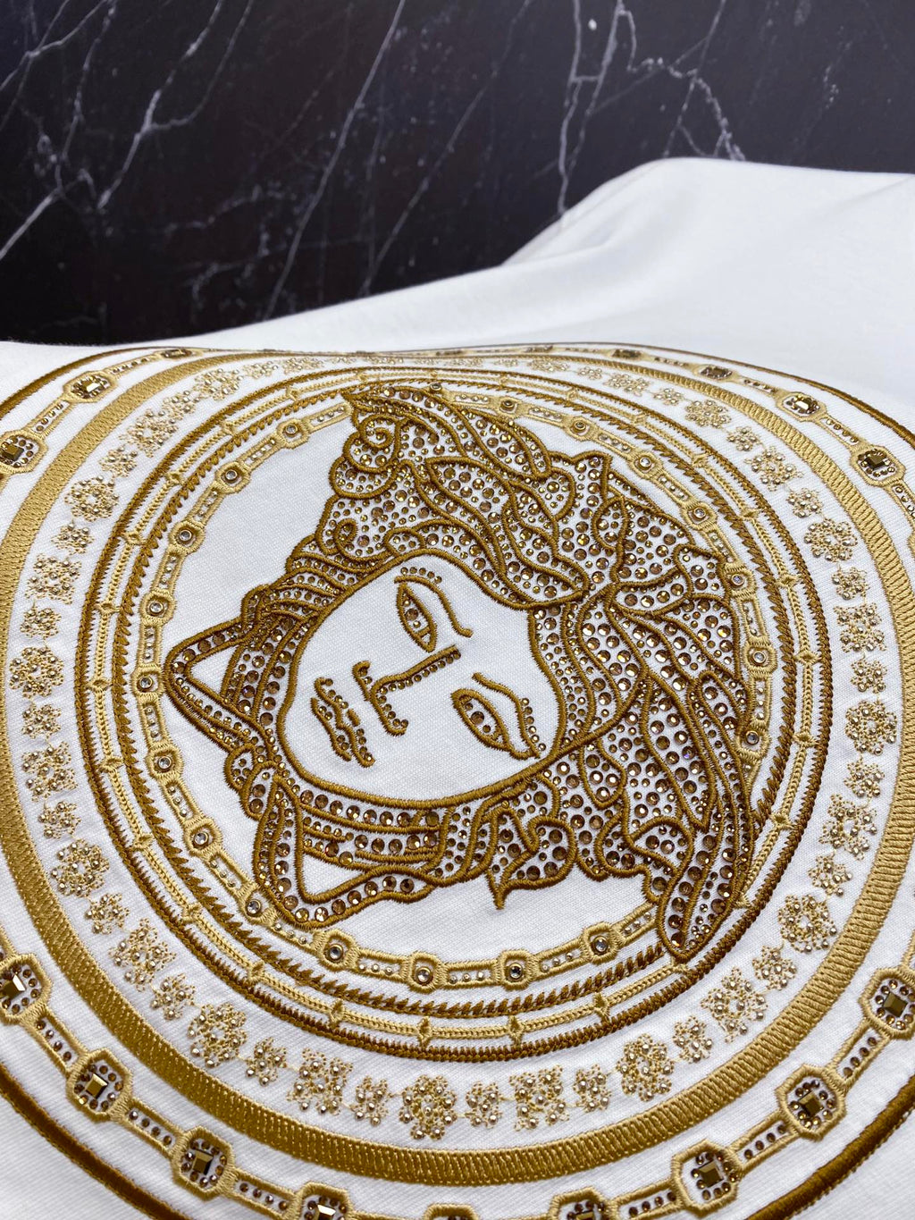 Versace white T-shirt close-up of gold ornate face medallion print