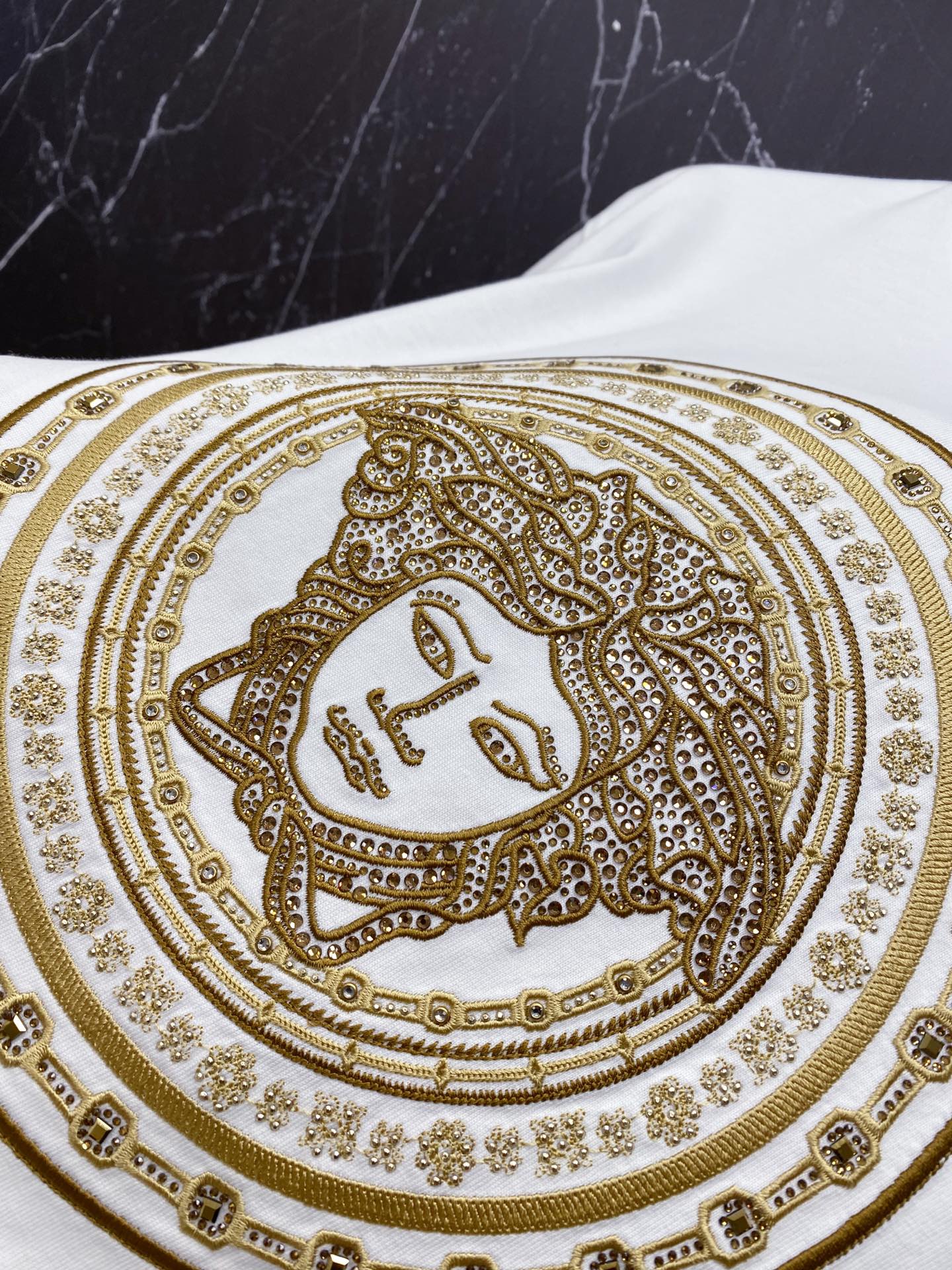 Versace white T-shirt close-up of gold ornate face medallion print