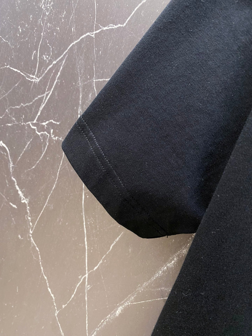 Versace black T-shirt sleeve and side hem close-up