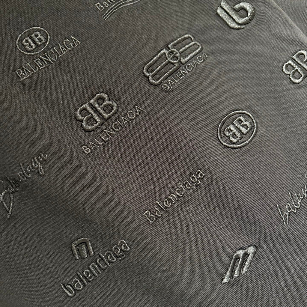 Black fabric close-up with raised tonal logo pattern and monograms