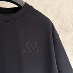 Black T-shirt front with small laurel-style logo emblem