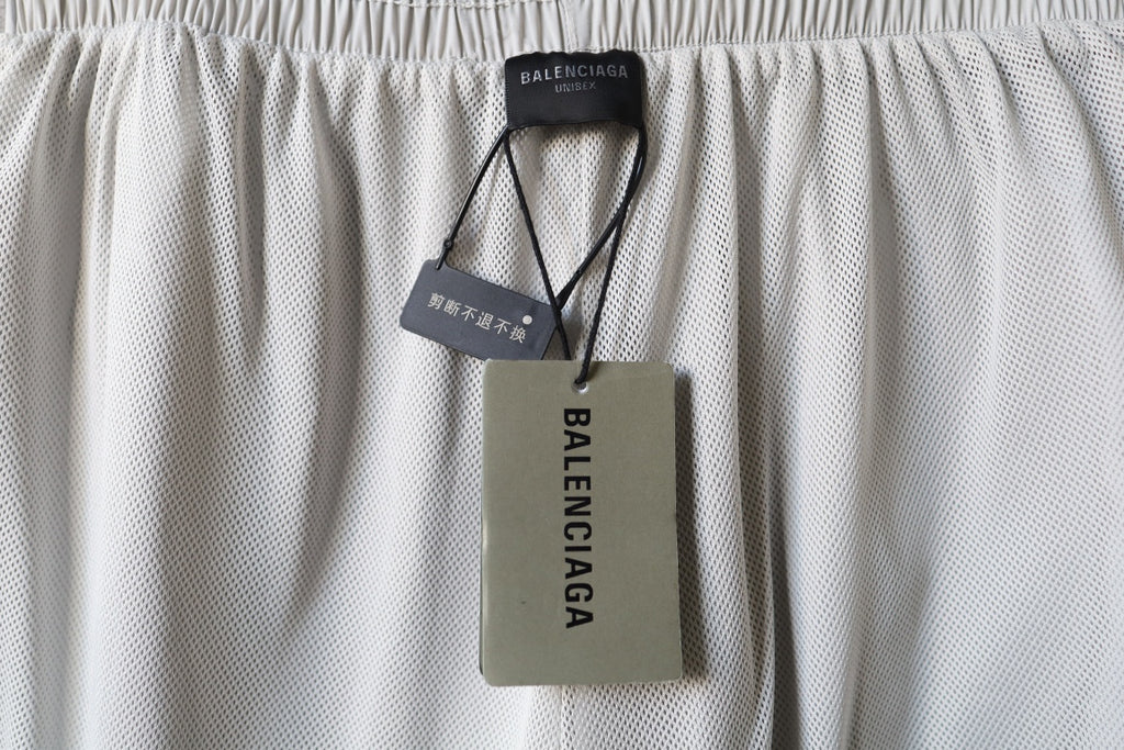 White Balenciaga pants with hanging fabric tags on waistband