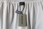 White Balenciaga pants with hanging fabric tags on waistband